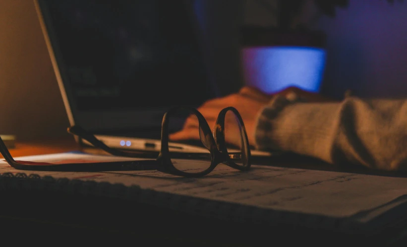 a laptop computer sitting on top of a wooden desk, a picture, by Elsa Bleda, pexels contest winner, realism, late night melancholic photo, glasses |, cinematic chiaroscuro, student