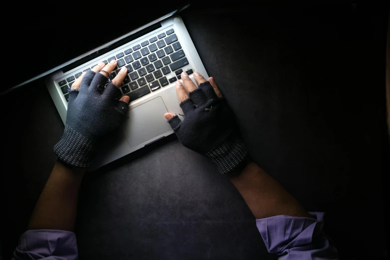 a person wearing gloves is typing on a laptop, by Everett Warner, pexels, computer art, holding arms on holsters, avatar image, dramatic shot, thumbnail