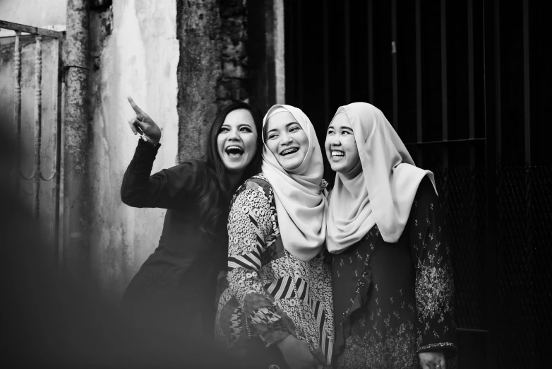 a couple of women standing next to each other, a black and white photo, by Basuki Abdullah, pexels contest winner, hurufiyya, she expressing joy, three women, good friends, pose 1 of 1 6