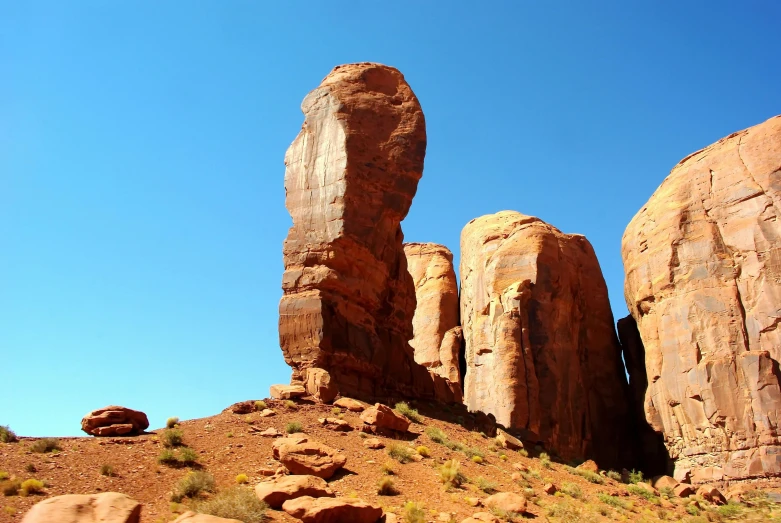 a large rock formation in the middle of a desert, a statue, by Jessie Algie, pexels contest winner, tall arches, twin towers, red sandstone natural sculptures, square masculine jaw