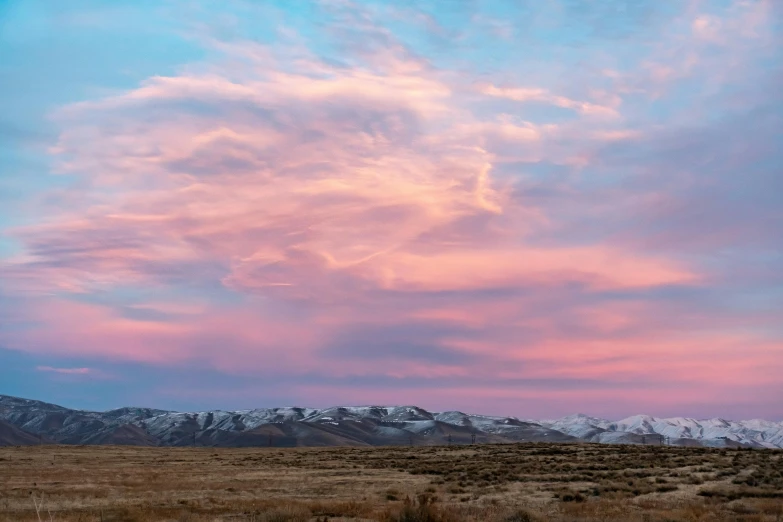 a field with snow covered mountains in the background, by Arnie Swekel, unsplash contest winner, romanticism, pink clouds in the sky, wyoming, sunset panorama, pink white turquoise