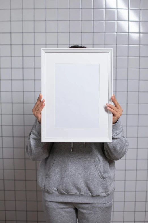 a woman holding a picture frame in front of her face, by Matthias Stom, unsplash, visual art, made of all white ceramic tiles, medium - format print, detailed product image, shrugging