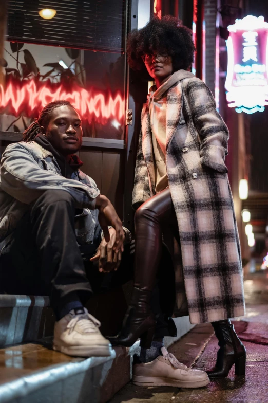 a couple of people sitting next to each other on a sidewalk, a portrait, by Amos Ferguson, trending on pexels, model wears a puffer jacket, : kendrick lamar, hero pose colorful city lighting, flannel