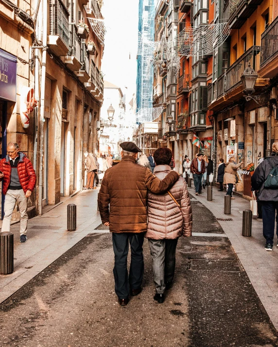 a man and a woman walking down a narrow street, pexels contest winner, lgbtq, two old people, standing in a city center, spanish