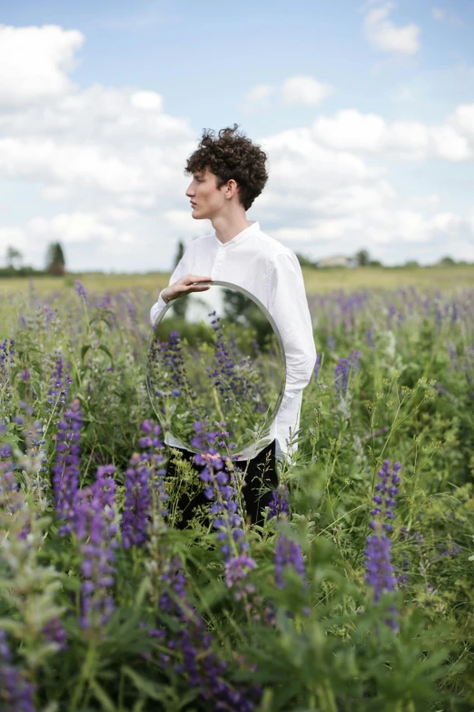 a man standing in a field of purple flowers, an album cover, inspired by Konstantin Somov, pexels contest winner, finn wolfhard, infinity mirror, model pose, mirrors