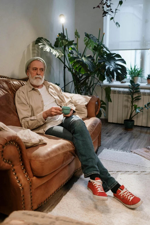 a man sitting on a couch in a living room, pexels contest winner, renaissance, bushy white beard, lgbtq, leonid, older male