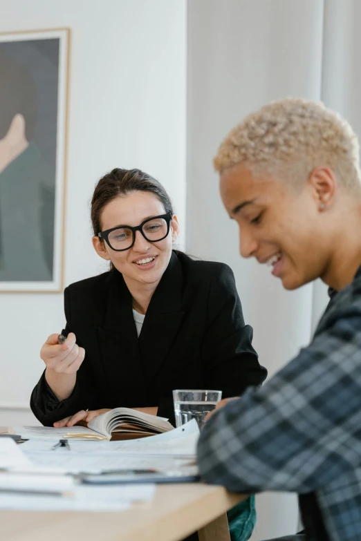 a group of people sitting around a wooden table, trending on pexels, academic art, wearing black frame glasses, androgynous male, woman holding another woman, professional image