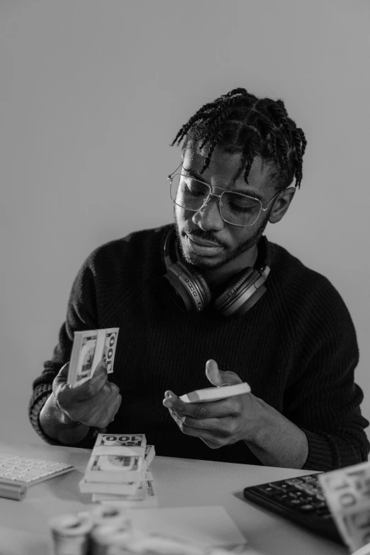 a man sitting at a table playing cards, a black and white photo, by Charles Martin, 2 1 savage, lossless, made of money, multi-part