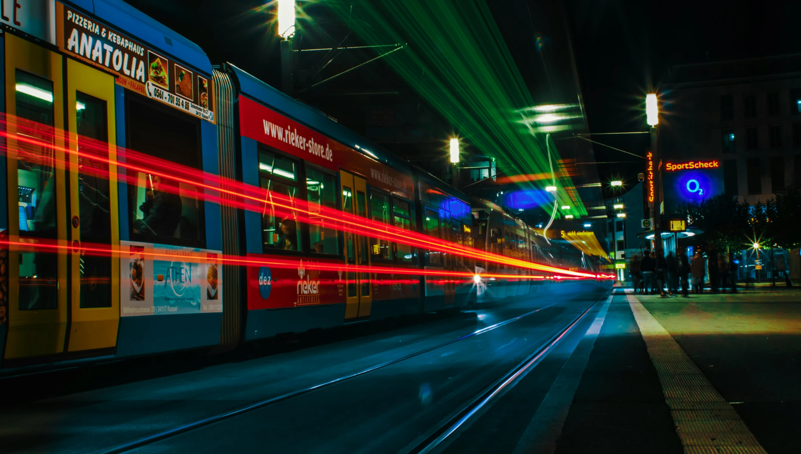 a train traveling down a city street at night, by Kristian Zahrtmann, pexels contest winner, happening, red and blue back light, green lines, thumbnail, celebrating