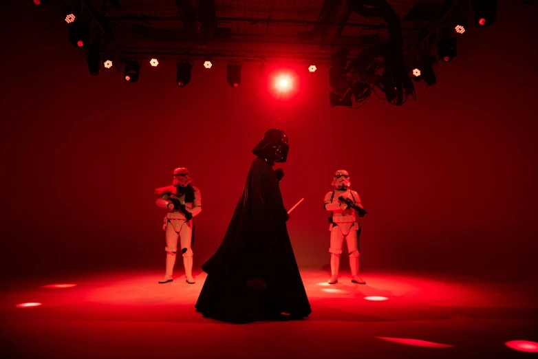 a group of people standing on top of a stage, a hologram, unsplash, wearing black sith uniform, 3 actors on stage, red light saber, kyoto studio