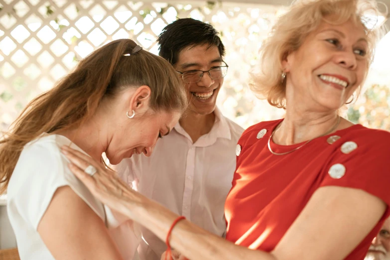 a group of people standing around each other, by Elizabeth Durack, pexels contest winner, happening, earing a shirt laughing, three women, wearing white cloths, upper body image