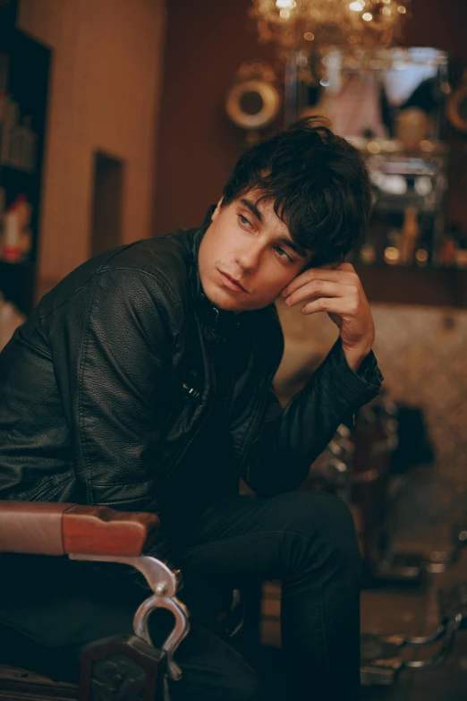 a man sitting on a chair in a room, an album cover, inspired by Adam Dario Keel, trending on pexels, neat hair with bangs, serious look, male teenager, leathery