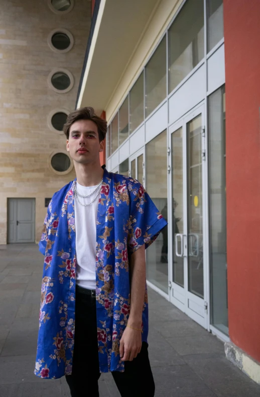 a young man standing in front of a building, an album cover, unsplash, renaissance, pale and coloured kimono, blue clothing, caspar david, street wear