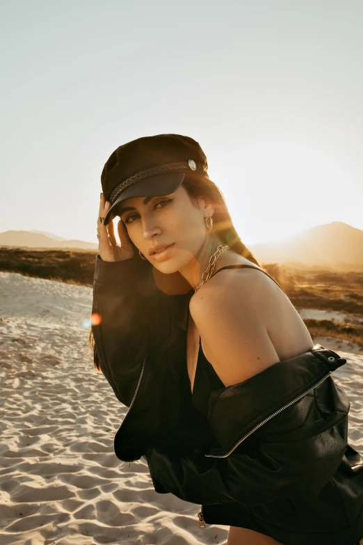a woman standing on top of a sandy beach, an album cover, trending on pexels, realism, kim kardashian as a cop, berets, anja millen, soft warm light