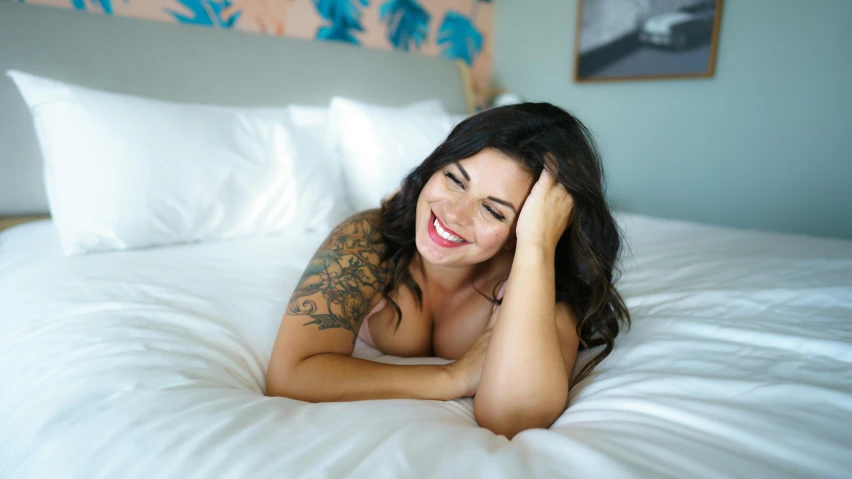 a beautiful young woman laying on top of a bed, by Jessie Algie, unsplash, manically laughing, buxom, inked, karla ortiz