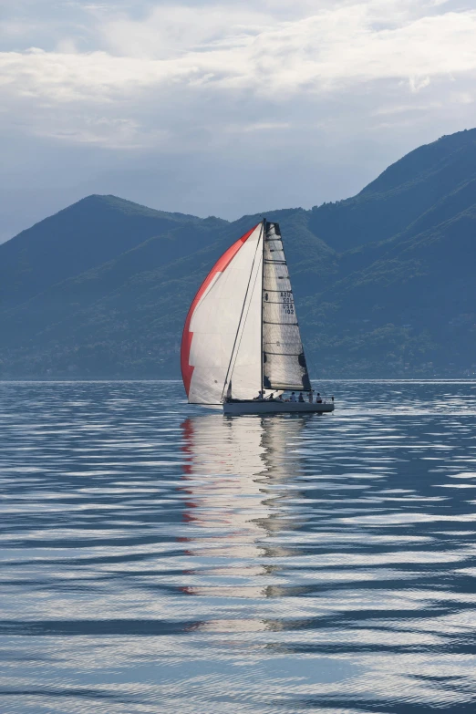 a sailboat in a body of water with mountains in the background, bizzaro, aerodynamic imposing