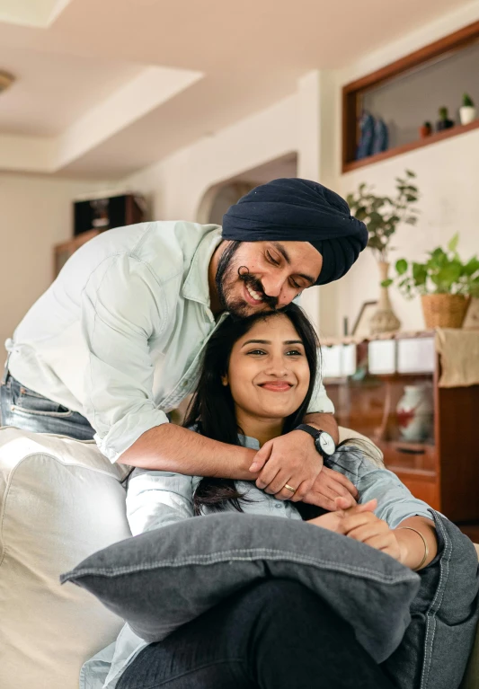 a man sitting on top of a couch next to a woman, inspired by Manjit Bawa, caring fatherly wide forehead, premium quality, couple on bed, dimples