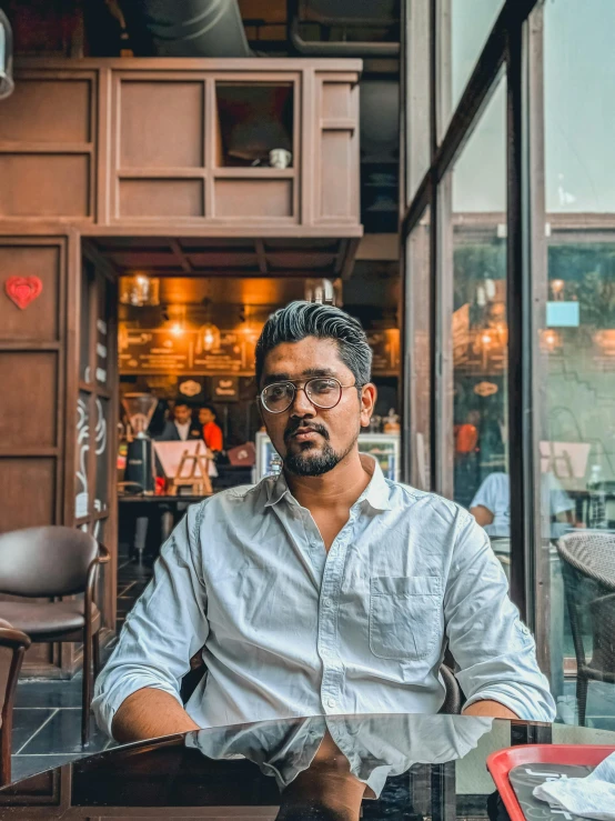 a man sitting at a table in a restaurant, a portrait, inspired by Bikash Bhattacharjee, pexels contest winner, renaissance, sitting on a mocha-colored table, portait photo profile picture, profile picture 1024px, ash thorp khyzyl saleem