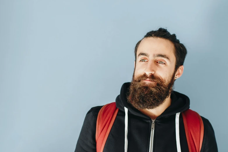 a man with a beard and a backpack, trending on pexels, avatar image, sparse chest hair, wearing a blue hoodie, awkward