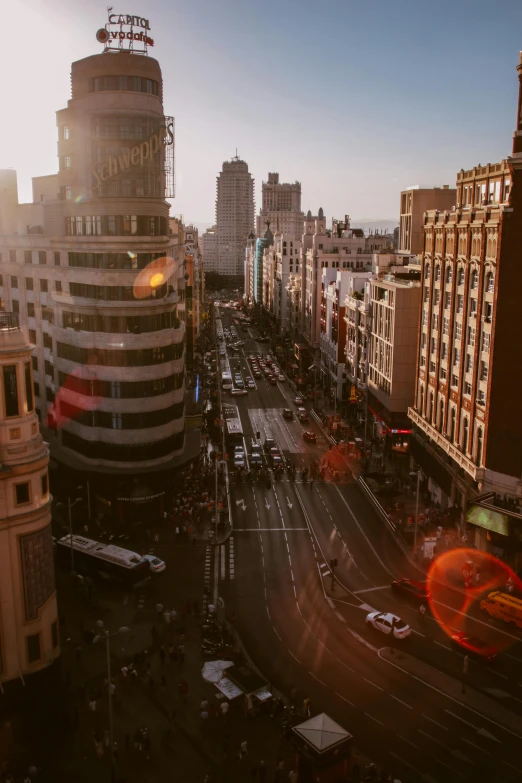 a city street filled with lots of traffic next to tall buildings, by Robbie Trevino, pexels contest winner, art nouveau, madrid, sun lighting from above, square, summer evening