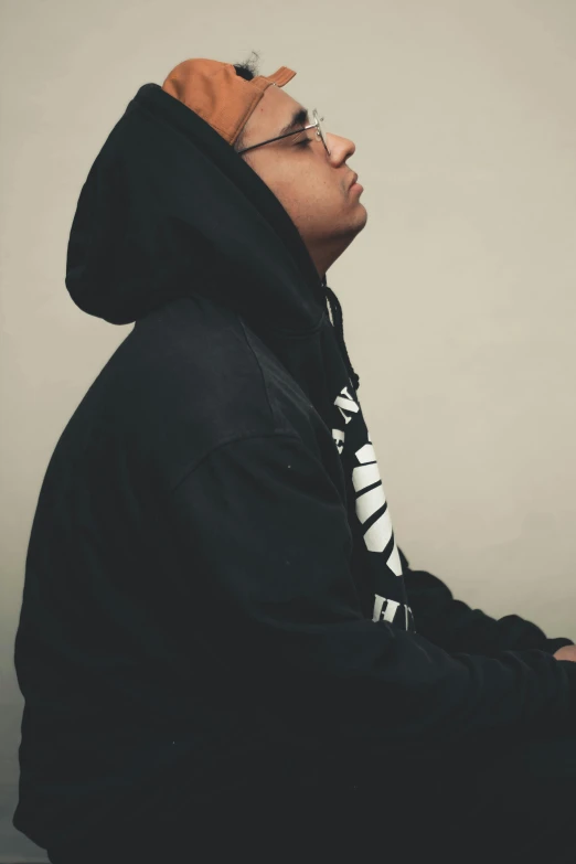 a man sitting in front of a laptop computer, an album cover, by Bascove, in a black hoodie, profile posing, smooth background, in 2 0 1 5