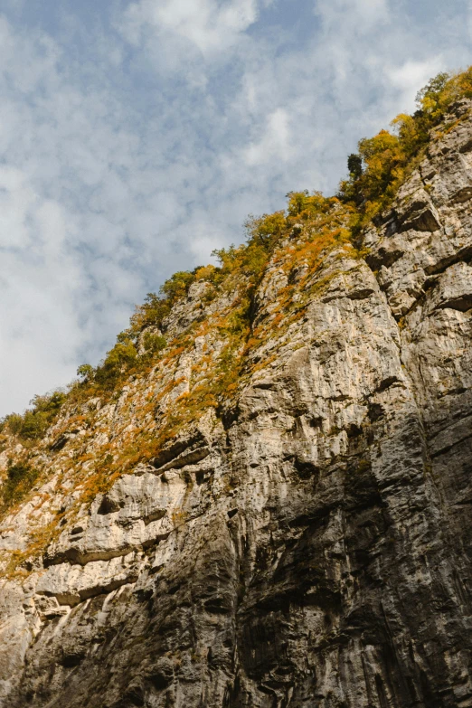 a man flying through the air while riding a skateboard, a picture, unsplash, hudson river school, chalk cliffs above, autum, st cirq lapopie, rock wall