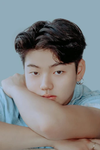 a young man sitting at a table with his arms crossed, inspired by Kim Myeong-guk, trending on pexels, headshot profile picture, twink, bbwchan, on a pale background