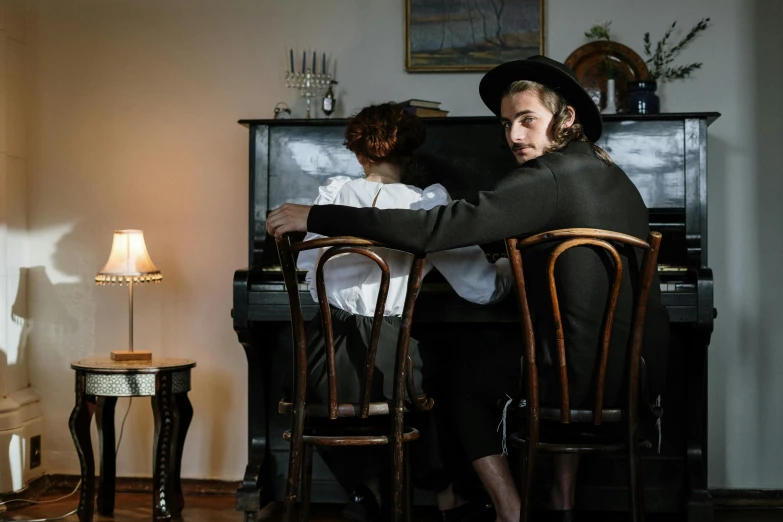 a man and a woman sitting at a piano, inspired by Vasily Perov, pexels contest winner, costumes from peaky blinders, long shot from back, hozier, ignant