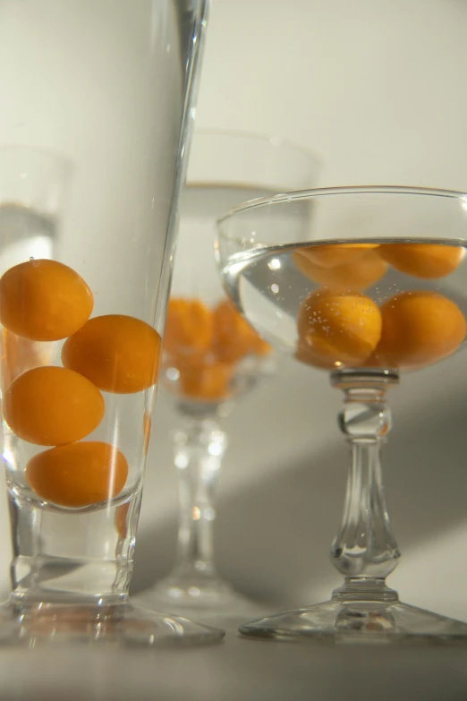 a number of glasses with oranges in them, inspired by Johannes Martini, soft natural volumetric lighting, cups and balls, medium-shot, mango