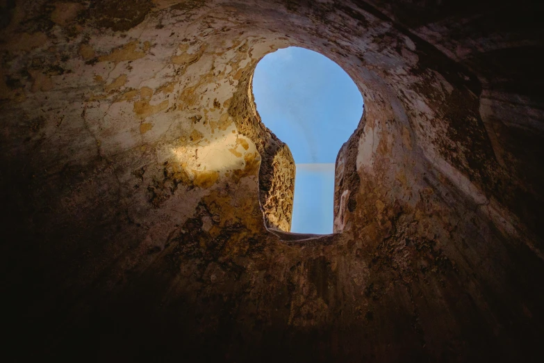 a view of the sky through a hole in a wall, by Eglon van der Neer, unsplash contest winner, romanesque, key hole on blue ball, warm light, promo image, brown