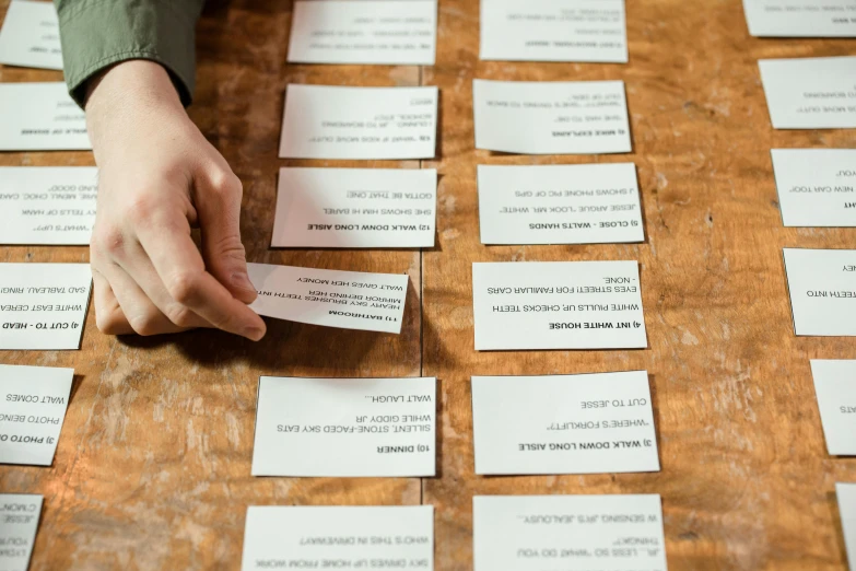 a person holding a piece of paper on top of a table, labels, ash thorp, cards, small manufacture