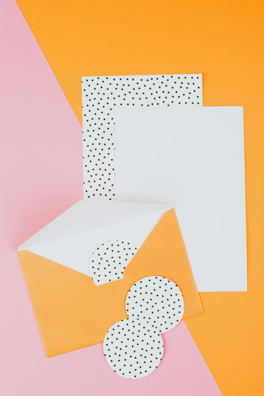 a couple of envelopes sitting on top of a pink and orange background, by Julia Pishtar, white with black spots, card template, greeting card, no - text no - logo