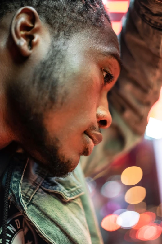 a close up of a person holding a cell phone, by William Berra, trending on pexels, visual art, handsome hip hop young black man, sitting alone at a bar, pensive, starry