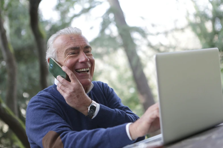 a man sitting at a table talking on a cell phone, pexels contest winner, both laughing, typing on laptop, nature outside, an oldman