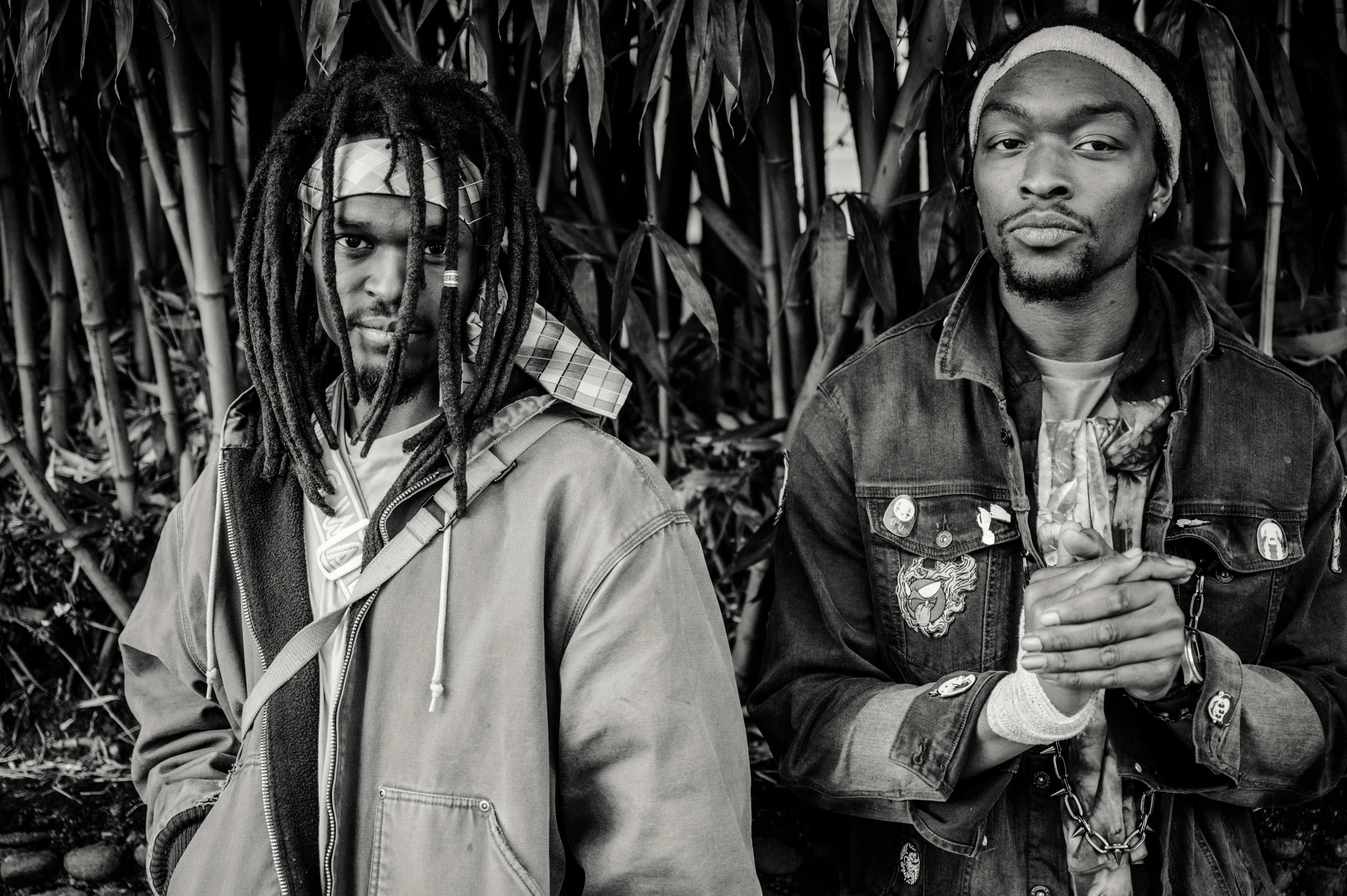 a couple of men standing next to each other, a black and white photo, by Nyuju Stumpy Brown, unsplash, black arts movement, dreadlock breed hair, band promo photo, seeds, shot with a camera flash