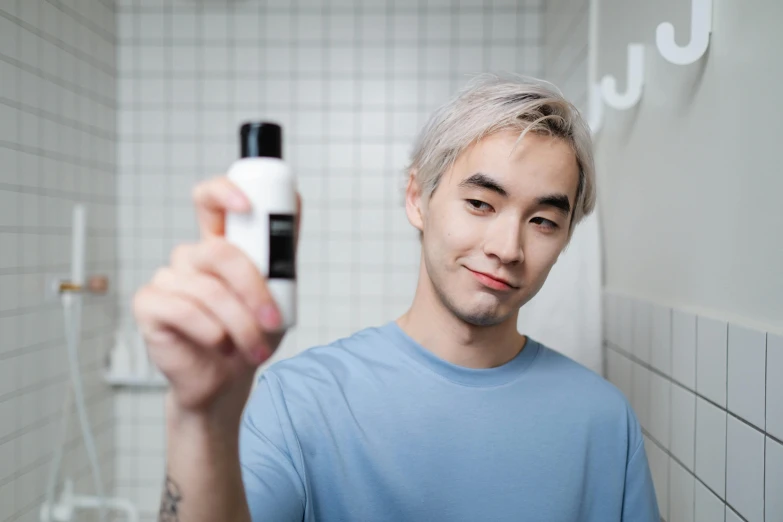 a man standing in a bathroom holding a bottle of shampoo, inspired by jeonseok lee, with a white complexion, with black, xqc, porcelain skin tone