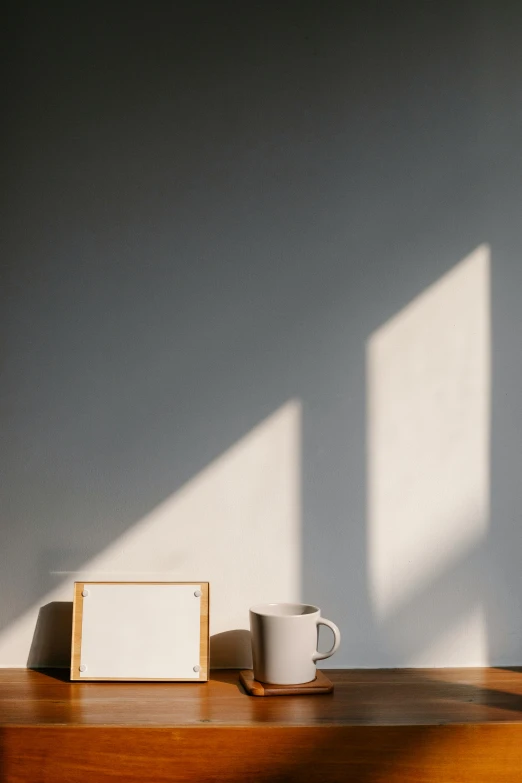 a picture frame sitting on top of a wooden table, a minimalist painting, by Eglon van der Neer, pexels contest winner, light and space, portrait of morning coffee, shadow play, two cups of coffee, background image