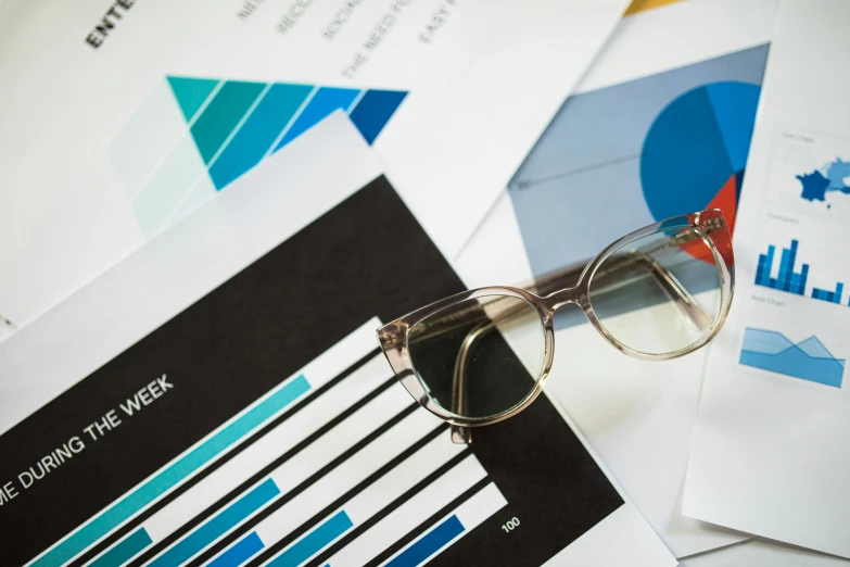 a pair of glasses sitting on top of a pile of papers, trending on unsplash, analytical art, graphs, white and blue color scheme, 15081959 21121991 01012000 4k, medium closeup shot