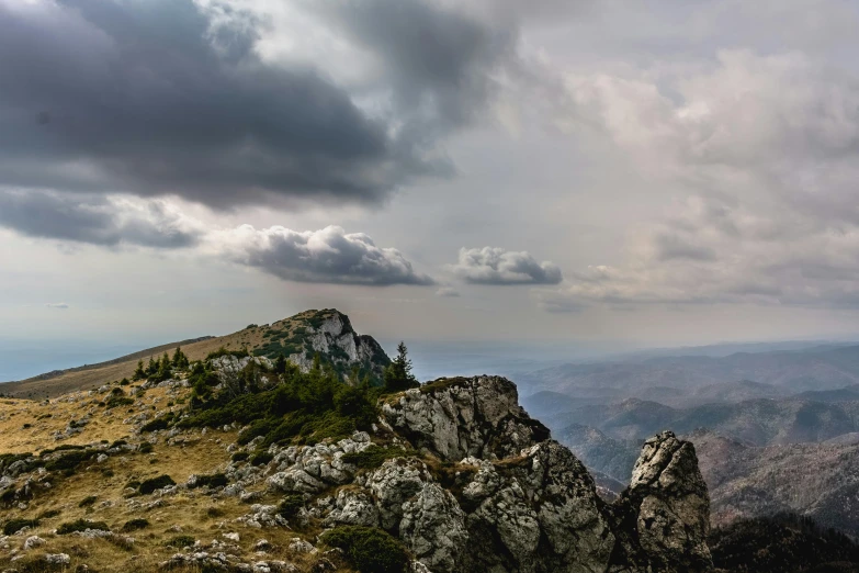 a person standing on top of a mountain on a cloudy day, by Adam Marczyński, pexels contest winner, romanticism, panoramic, limestone, colour photo, slide show
