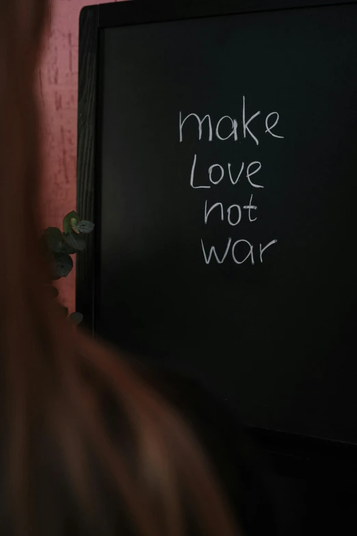 a woman standing in front of a tv writing make love not war, pexels, paul barson, a person standing in front of a, black in, support
