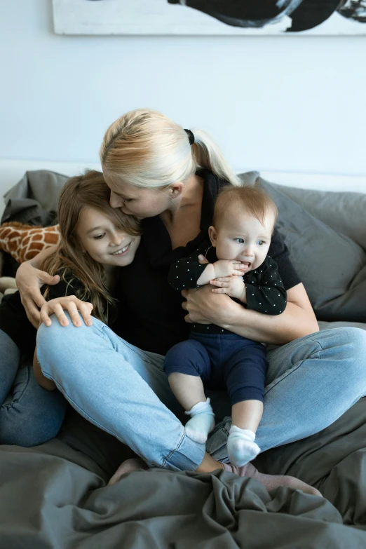 a woman and two children sitting on a couch, pexels contest winner, incoherents, holding each other, blond, toddler, black