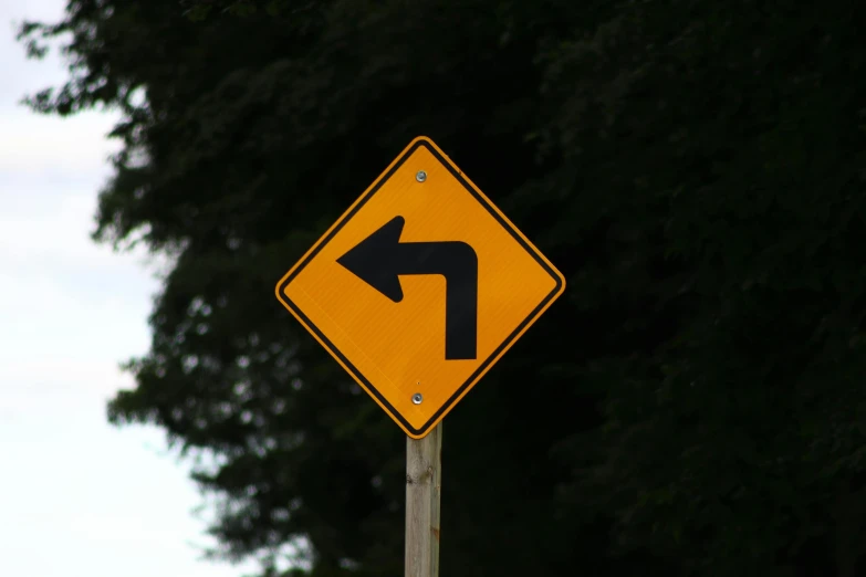 a close up of a street sign with a tree in the background, by David Garner, unsplash, hurufiyya, showing curves, zig zag, left trad, yellow