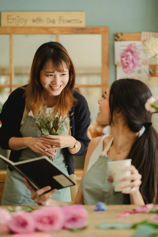 two women talking to each other in a flower shop, by Reuben Tam, pexels contest winner, renaissance, holding notebook, ( waitress ) girl, promo image, japanese collection product