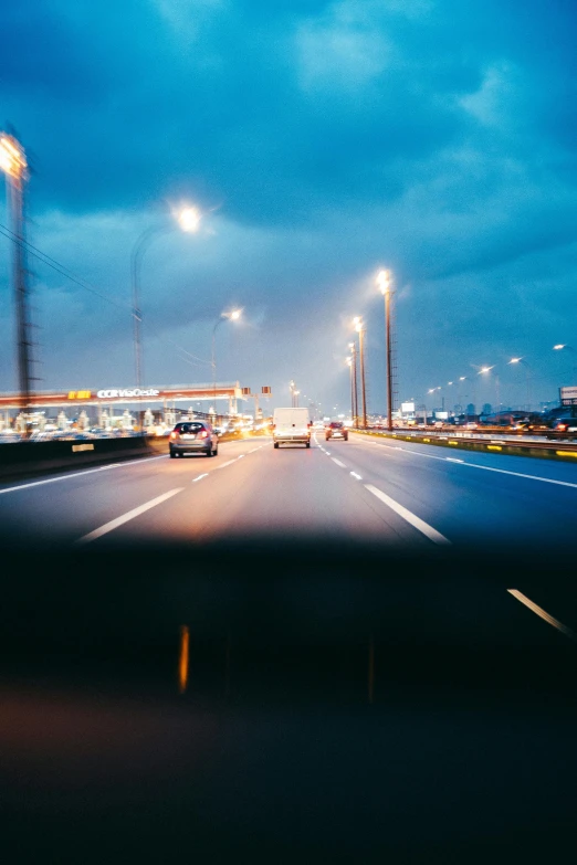 a blurry photo of a highway at night, by Jacob Toorenvliet, unsplash, blue headlights, gloomy lights in the sky, photo of futuristic cityscape, riding on the road