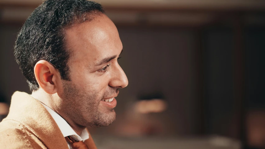 a close up of a person wearing a suit and tie, inspired by Afewerk Tekle, les nabis, he is wearing a brown sweater, close - up profile, mo salah, caring fatherly wide forehead