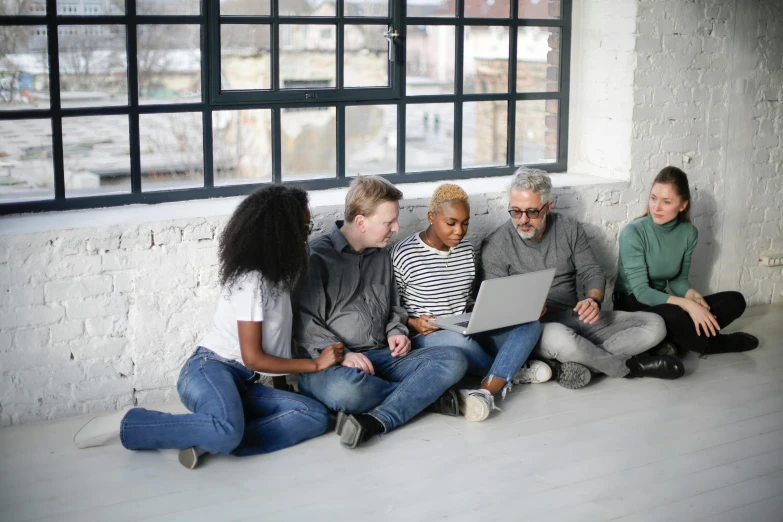 a group of people sitting on the floor looking at a laptop, by Carey Morris, pexels, renaissance, diverse, grey, background image, leaders