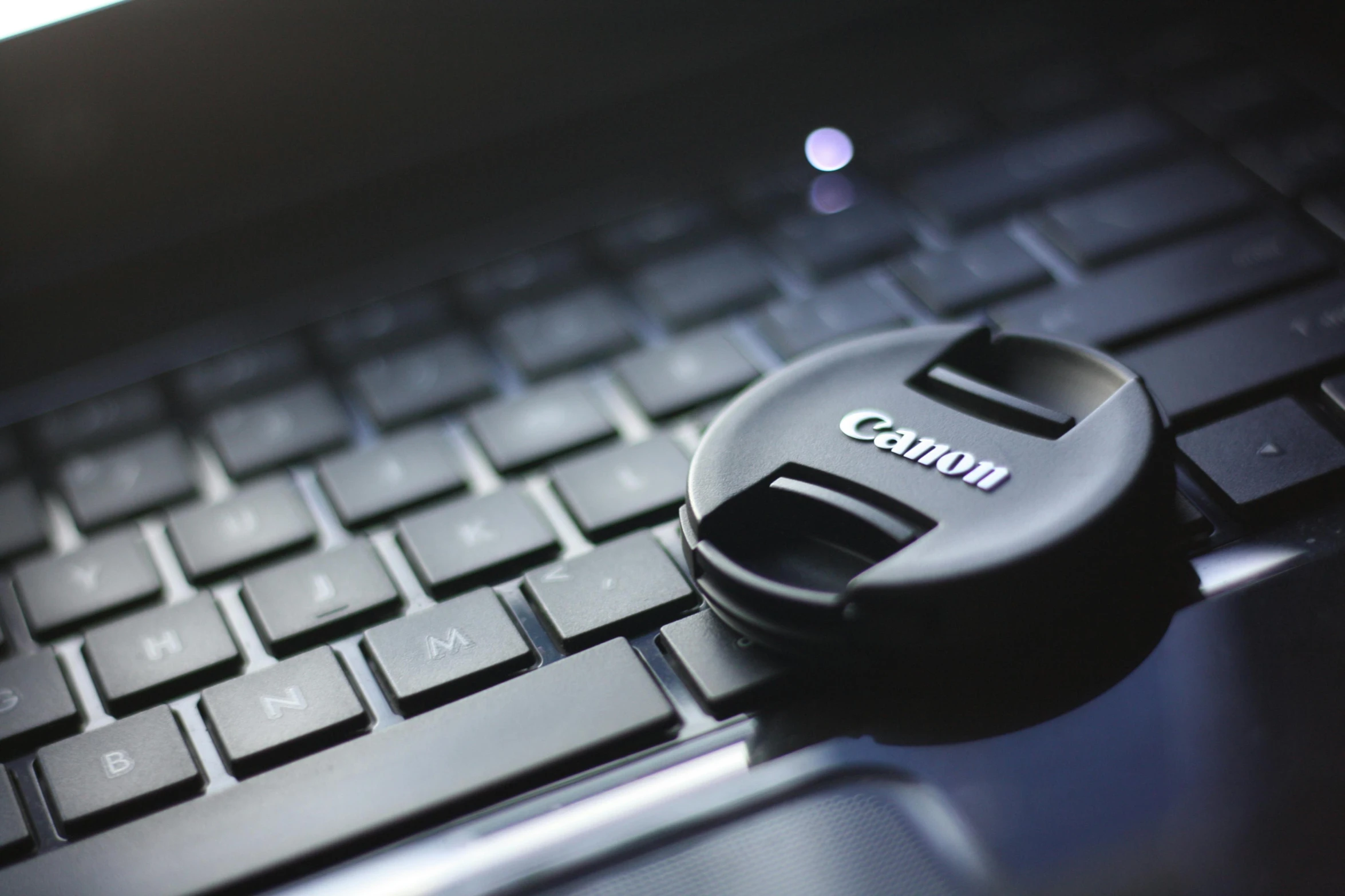 a close up of a camera lens cap on a laptop keyboard, a picture, by Carey Morris, unsplash, canon eos 5d mark 2, (canon, bottom angle, contain