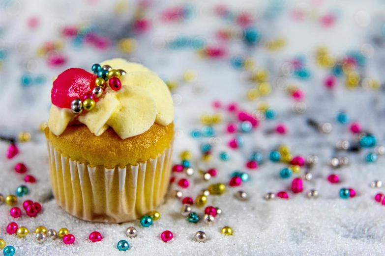 a cupcake sitting on top of a table covered in confetti, trending on pexels, jewelry pearls, romanian, studio shoot, sugar snow