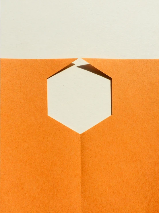 an orange envelope with a hexagon cut out of it, inspired by Frederick Hammersley, unsplash, postminimalism, detailed product image, portrait close - up, portal opening, cartouche