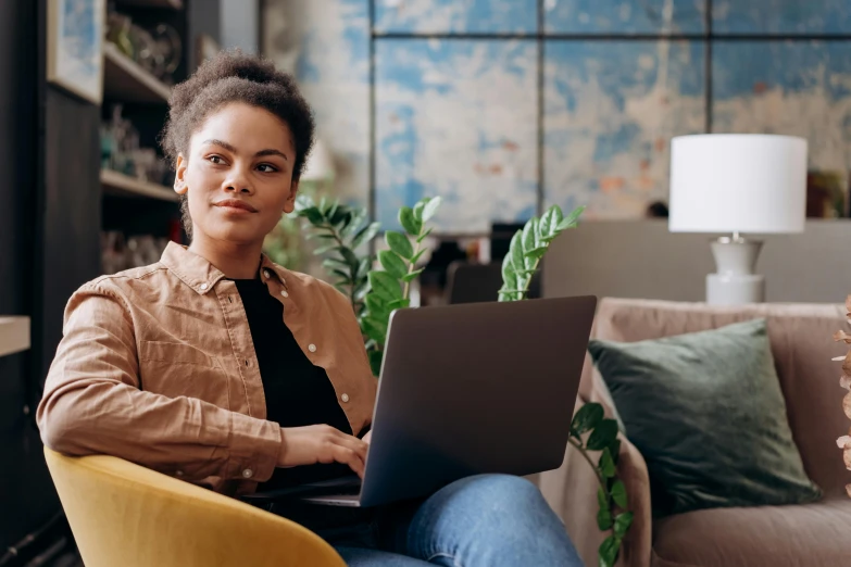 a woman sitting in a chair with a laptop, a portrait, trending on pexels, mixed-race woman, thumbnail, brown, developers